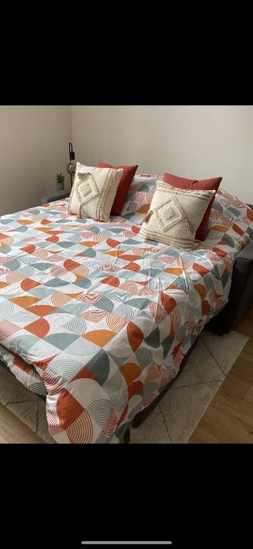 - un lit avec une couette et des oreillers colorés dans l'établissement Le Cocon Studio Auxerre Centre, à Auxerre