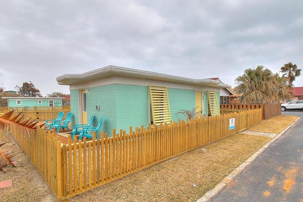 ein blaues Haus mit Stühlen vor einem Zaun in der Unterkunft Kona Cottage at Spanish Village in Port Aransas