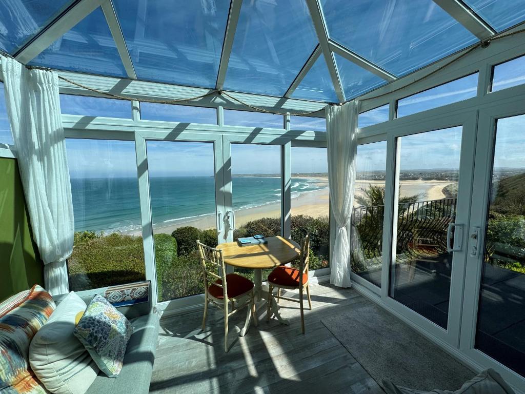 a conservatory with a table and a view of the ocean at Huers Hide in Carbis Bay