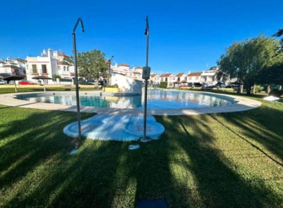 a swimming pool in the middle of a park at APARTAMENTO APARTACLUB REFORMADO in Chiclana de la Frontera