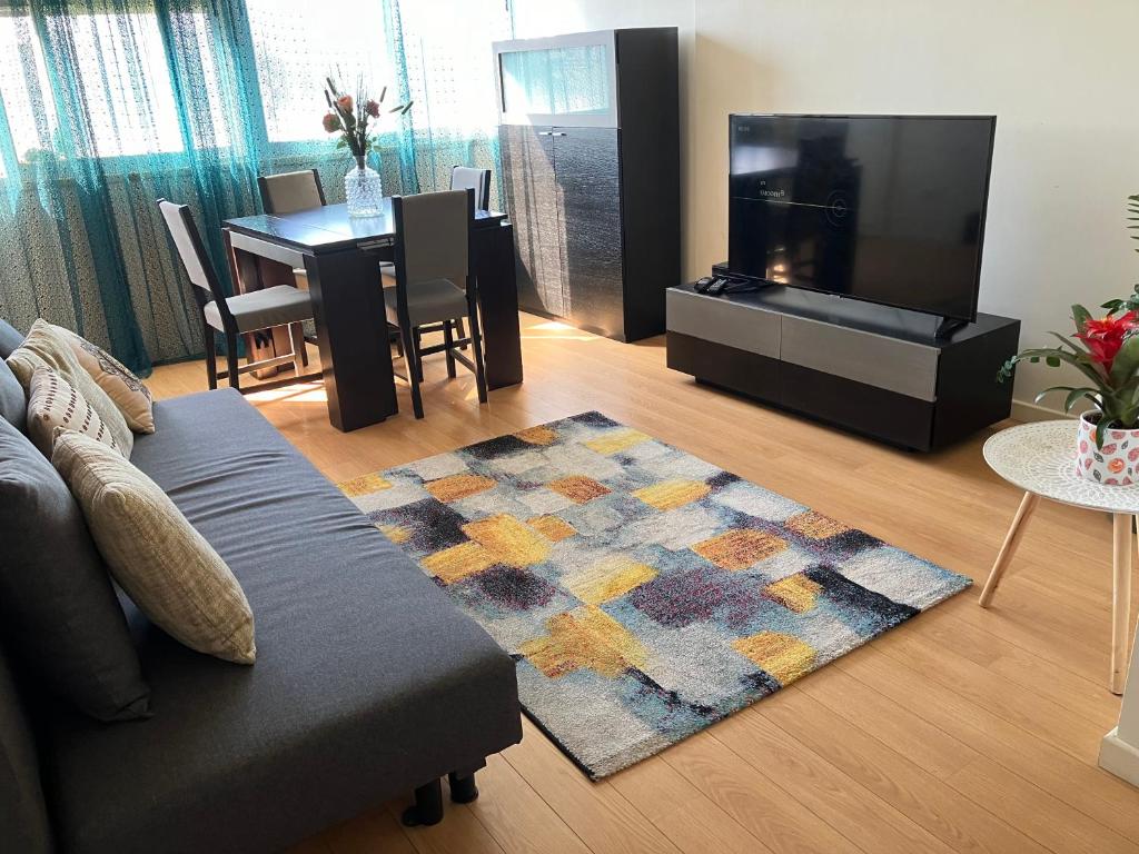 a living room with a couch and a flat screen tv at Sol da Caparica in Costa da Caparica