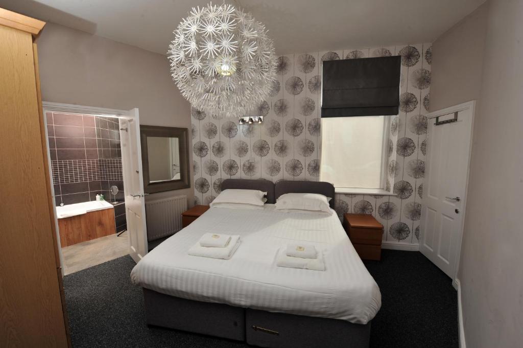 a bedroom with a large bed and a chandelier at Harrogate Self Catering -Harrogate Convention View - Parking in Harrogate