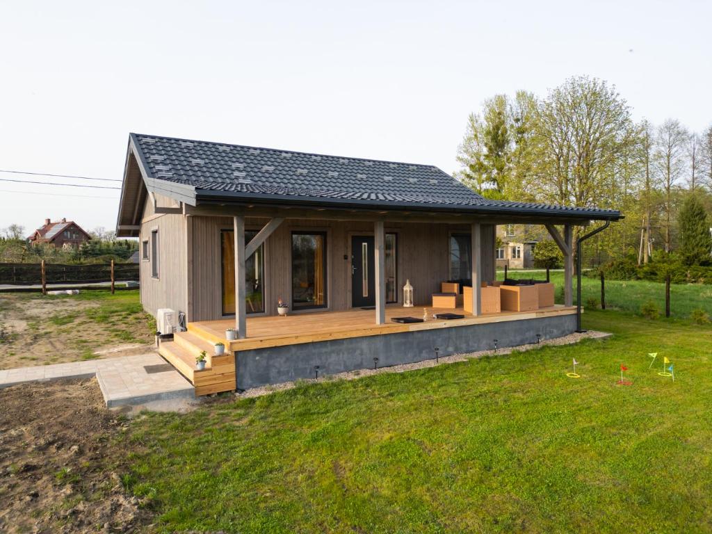uma pequena casa com um grande deque num quintal em NCNK Lawendowy Domek em Iława