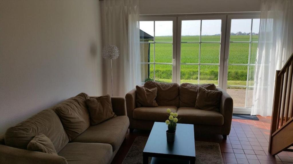 ein Wohnzimmer mit einem Sofa, einem Tisch und einem Fenster in der Unterkunft Ferienhäuser Freiblick in Ditzumerverlaat