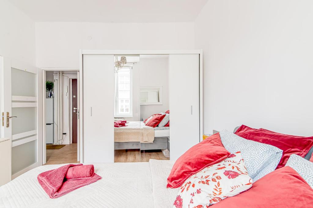 a bedroom with a mirror and a bed with red pillows at Szeroka Royal Rooms in Gdańsk