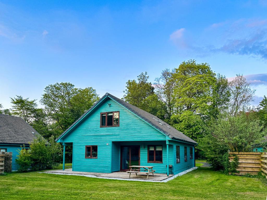 una casa azul con una mesa de picnic en el patio en Foxglove Cottages, en Drymen