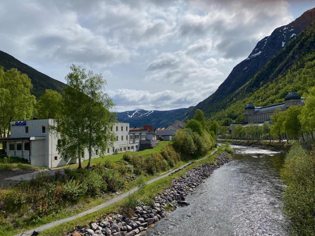 a river in a town with mountains in the background at Rjukan Gjestegård in Rjukan