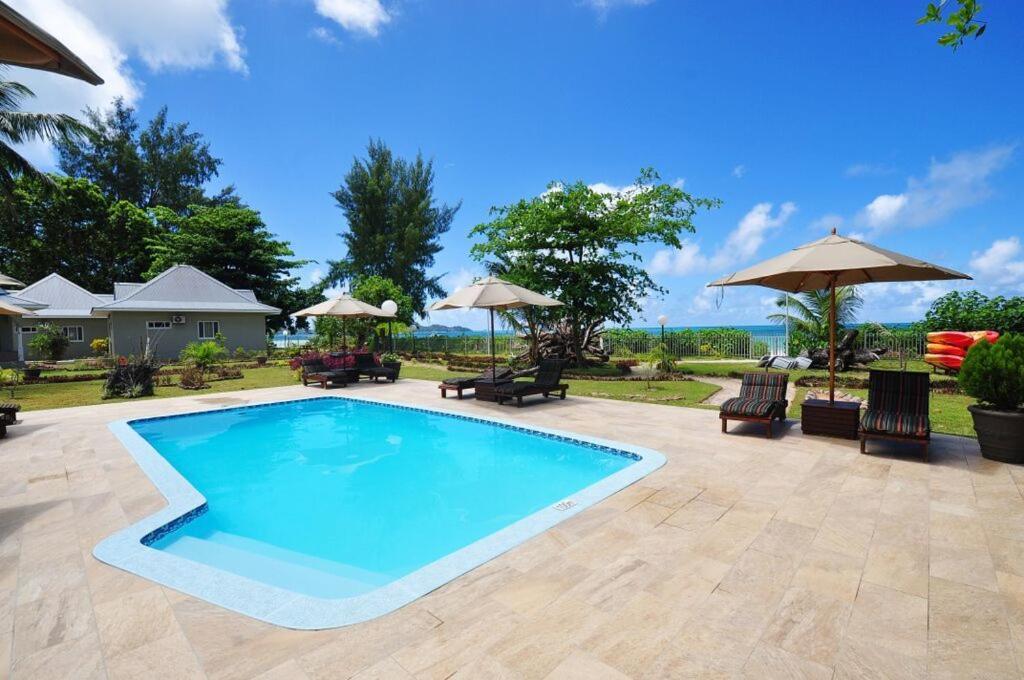 una piscina con sillas y sombrillas en un patio en Cote d'Or Footprints en Baie Sainte Anne