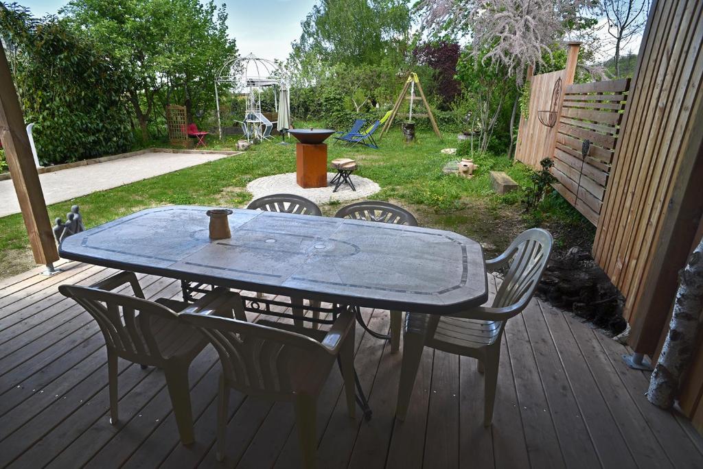 - une table et des chaises sur une terrasse avec une aire de jeux dans l'établissement Gite Le Douglas, Vignoble et Reculées du Jura - Avec Sauna, à Lavigny