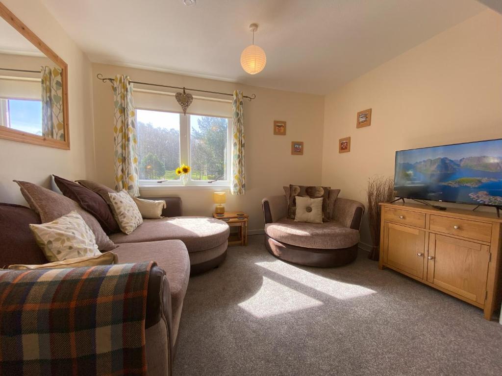 uma sala de estar com um sofá e uma televisão de ecrã plano em Treetops - Bright 2 Bed Flat - Super Location em Inverness