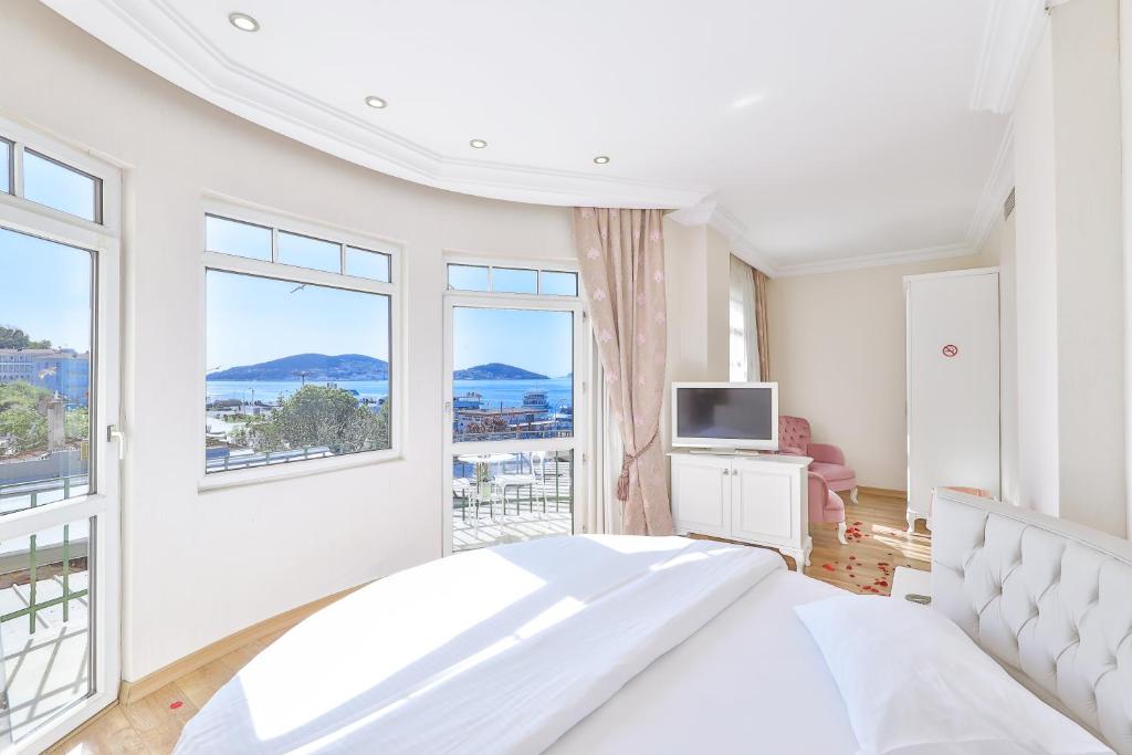 a white bedroom with a bed and a large window at Buyukada Princess Hotel in Buyukada