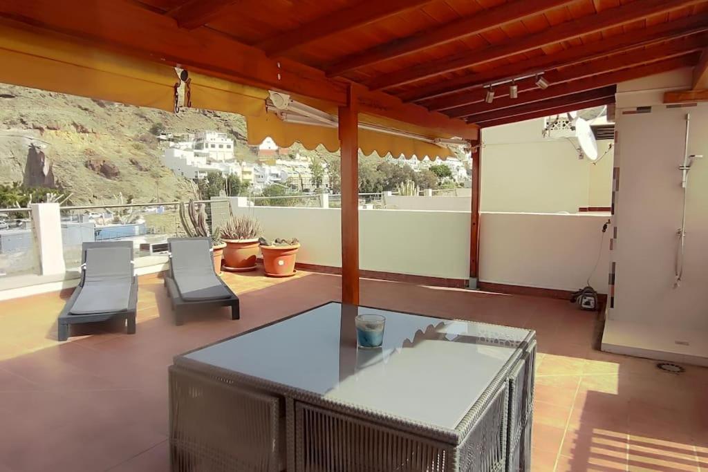 a patio with a table and chairs and a mountain at Paraíso con gran solarium privado en playa Mogán in Puerto de Mogán