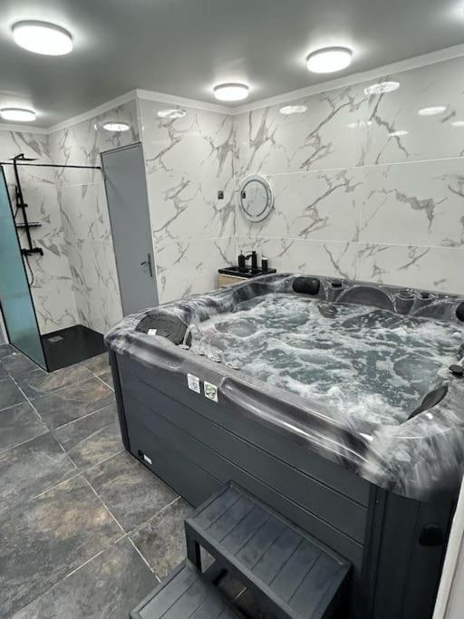een groot bad in een badkamer met een marmeren muur bij White Spa by Gold Spa in Roubaix