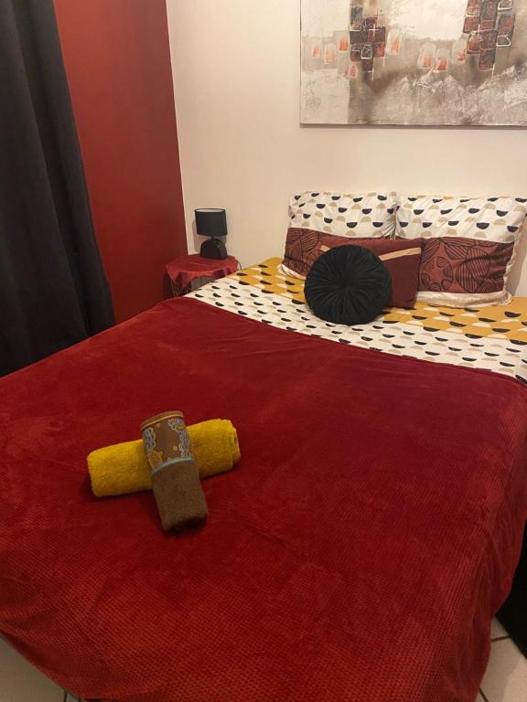 Un dormitorio con una cama roja con una cruz. en Chambre dans maison proche Disneyland Paris, en Brie-Comte-Robert