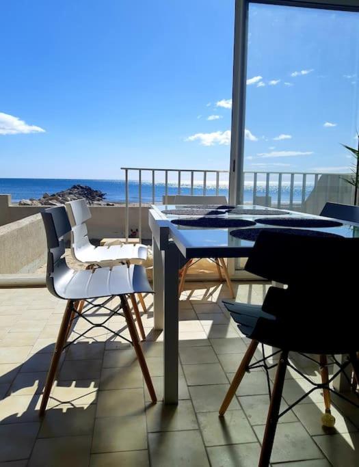 une table et des chaises sur un balcon avec vue sur l'océan dans l'établissement LES PIEDS DANS L'EAU, à Palavas-les-Flots