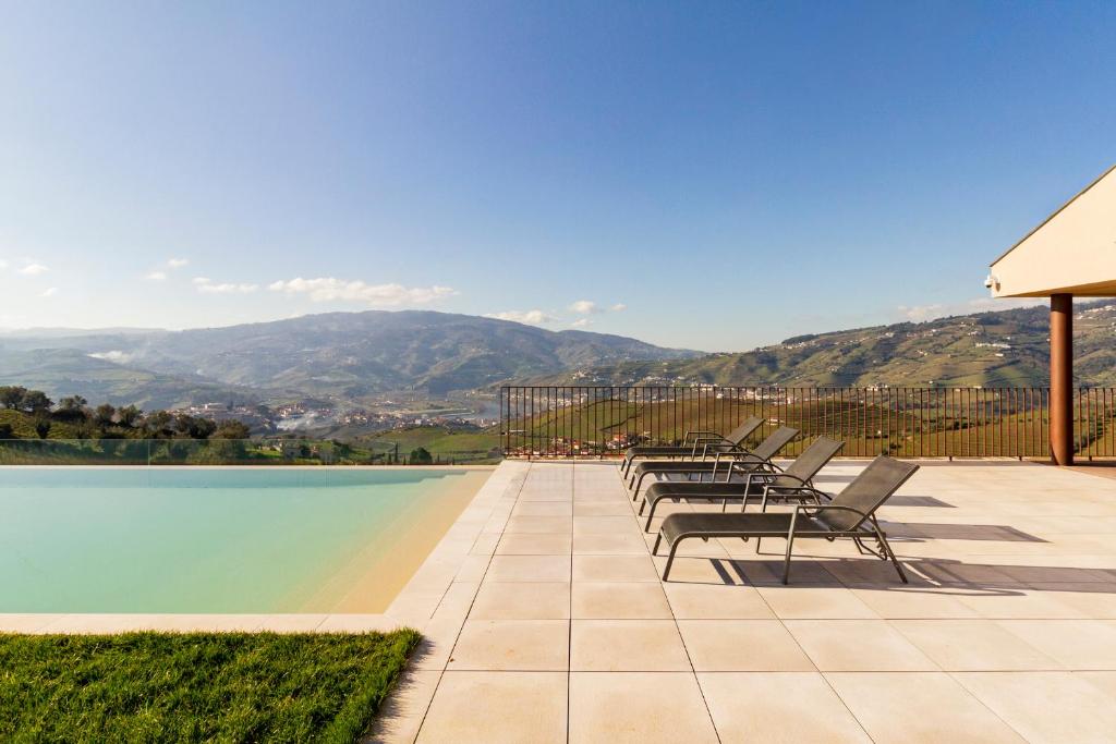 a row of chairs sitting next to a swimming pool at Luxury Vineyard Home with Infinity Pool in Douro Valley in Santa Marta de Penaguião