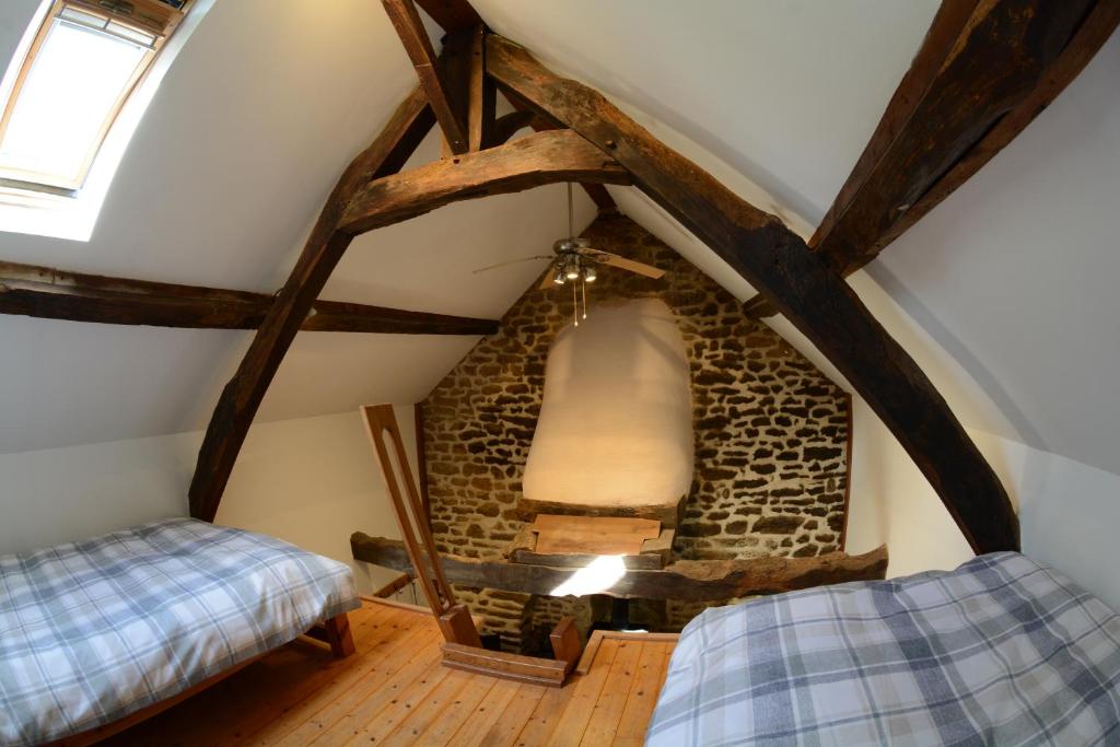 a attic room with a stone fireplace and two beds at La Paisière in Montaudin