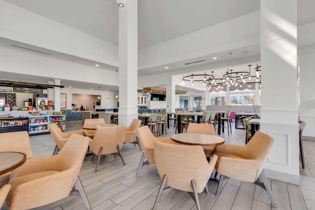Hilton Garden Inn Myrtle Beach/Coastal Grand Mall في ميرتل بيتش: غرفة طعام مع طاولات وكراسي في مطعم