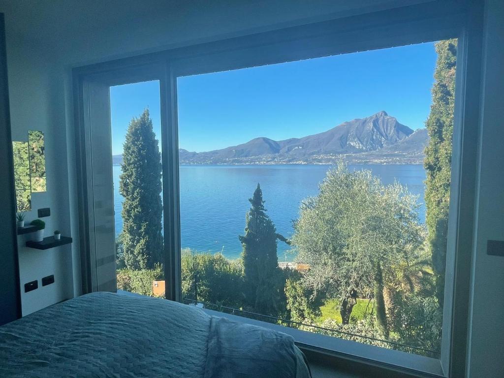 1 dormitorio con una gran ventana con vistas al agua en 3 Zimmer Apartment am Gardasee mit traumhaften Seeblick und Pool in Torri del Benaco, en Torri del Benaco