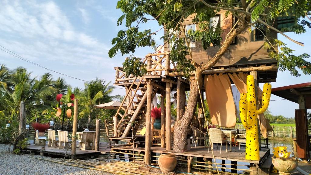 a tree house with chairs and a tree at Villa De Lumhun in Lamphun