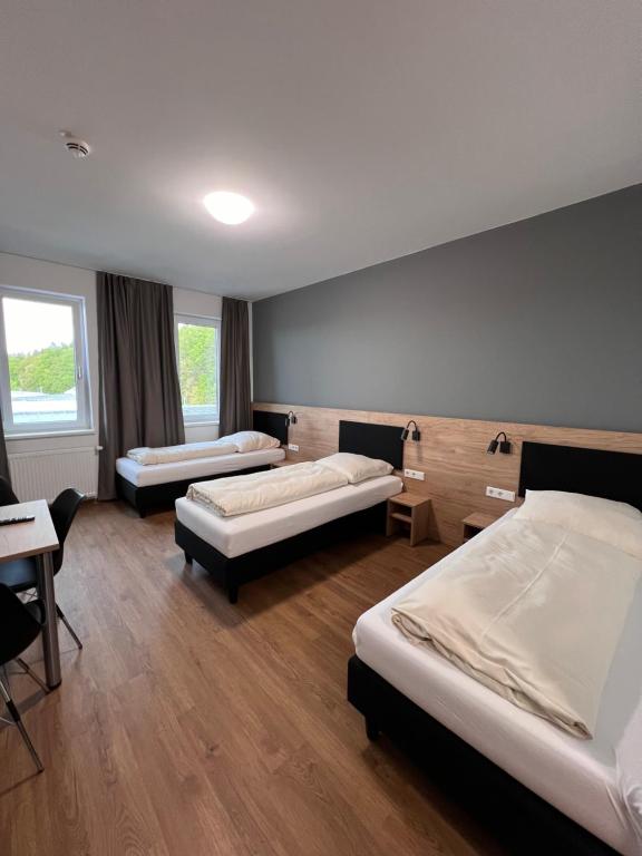エーバースベルクにあるFirstsleep Ebersbergのベッド3台、テーブル、椅子が備わる客室です。