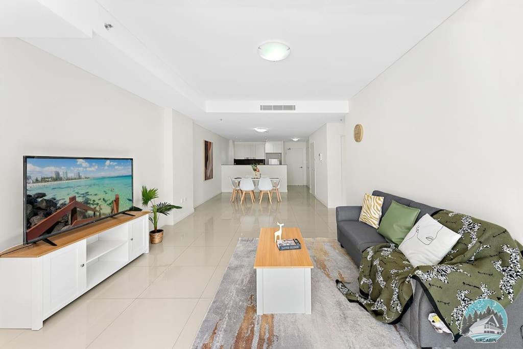 a living room with a couch and a tv at Aircabin - Mascot - Walk to Station - 3 Beds Apt in Sydney
