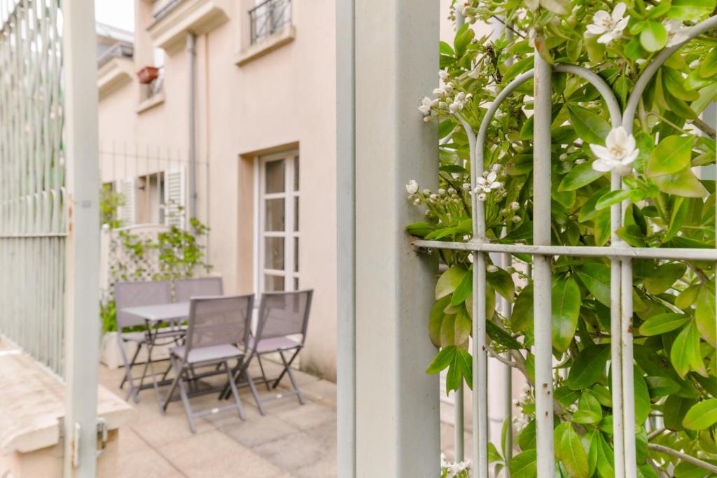 - un balcon avec une table, des chaises et des fleurs dans l'établissement EXIGEHOME-Maison avec terrasse privée, à Versailles