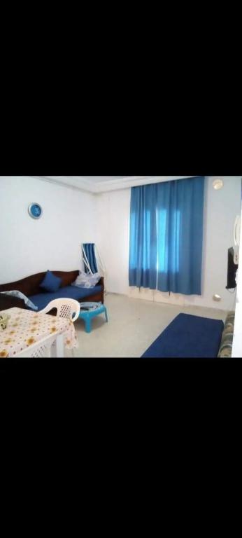 Un dormitorio con una cortina azul y un sofá. en شط مريم, en Hammam Sousse