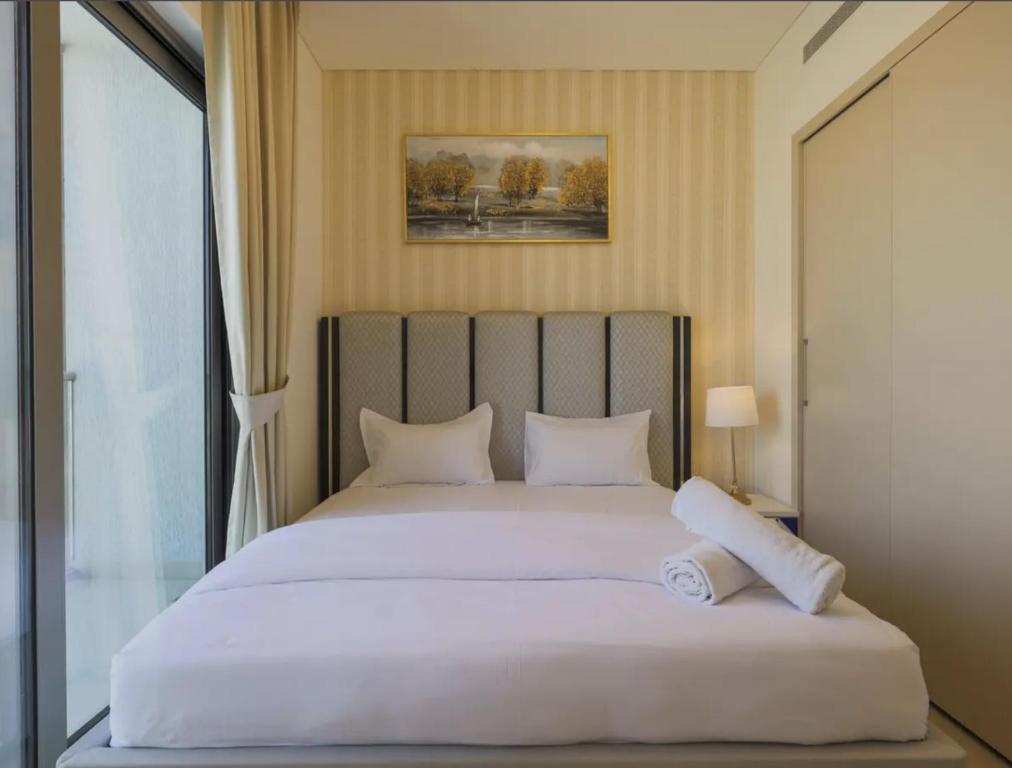 een slaapkamer met een groot wit bed en een raam bij Living in a Tower in Downtown - Extravagance at a Budget Price - Only 5 Minutes’ Walk to Dubai Mall in Dubai