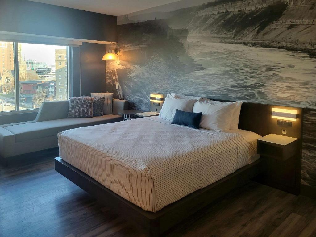 a bedroom with a bed and a painting of the ocean at Cambria Hotel Niagara Falls in Niagara Falls