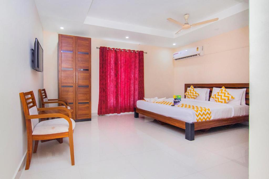 1 dormitorio con cama y cortina roja en FabHotel Krishna Residency, en Chennai