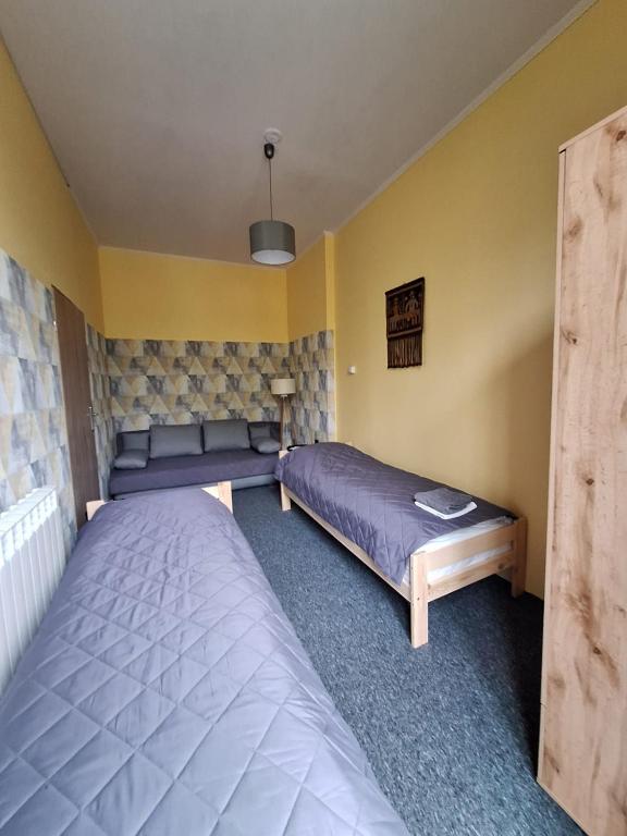 two beds in a room with yellow walls at Za zieloną bramą in Zawiercie