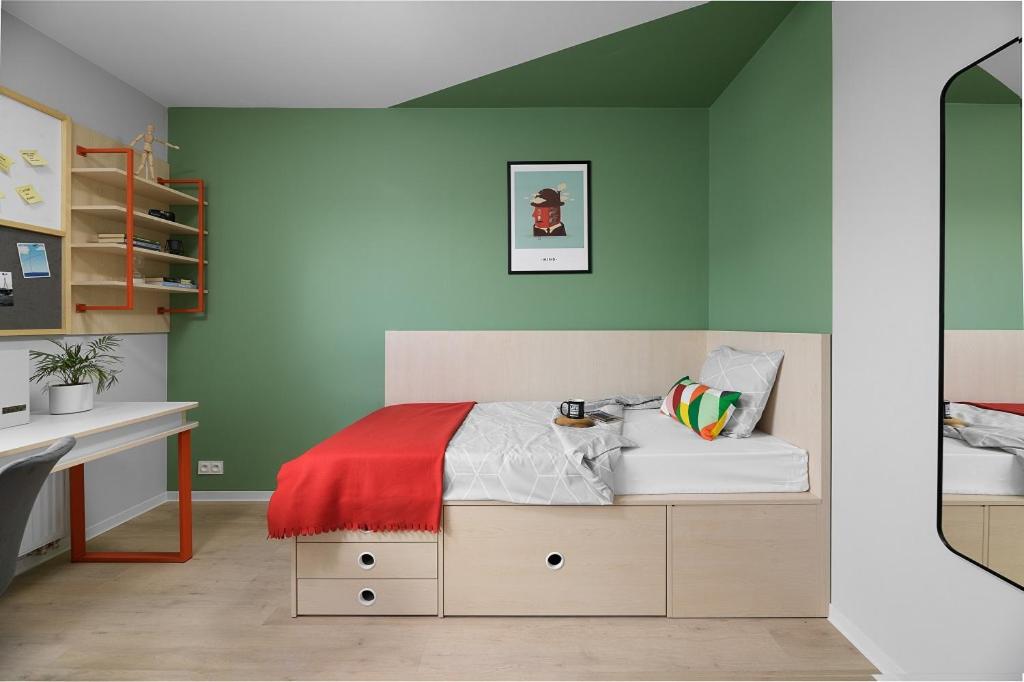 - une chambre avec des murs verts et un lit avec un bureau dans l'établissement Student Depot Lublin Apartamenty, à Lublin