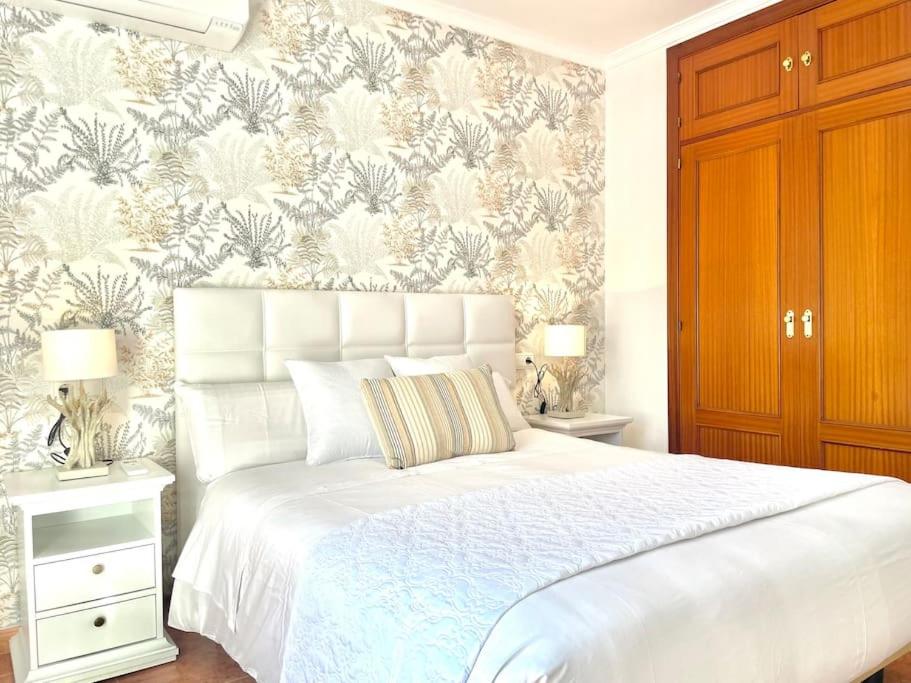 a bedroom with a white bed with a floral wallpaper at LaFrenchTouch - Céntrico y moderno cerca del tren in Benalmádena