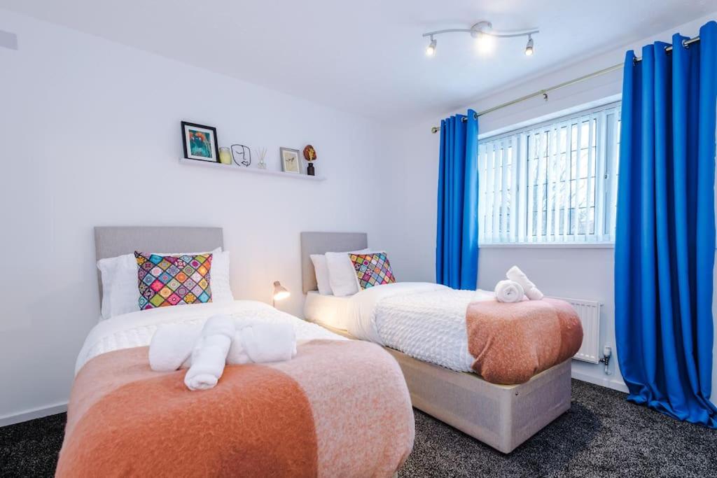 2 letti in una camera da letto con tende blu di 3 Bed+2 Bath Perfect Contractors & Groups a Ocker Hill