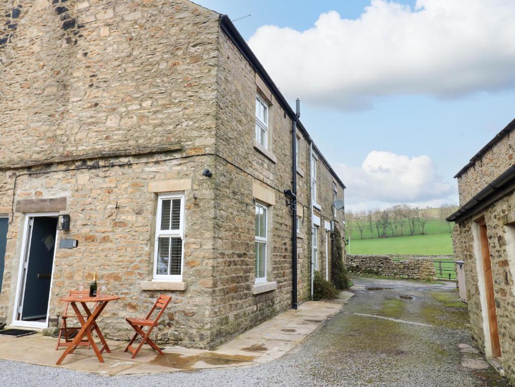 - un bâtiment en briques avec une table et des chaises à l'extérieur dans l'établissement Larl Cottage, à Barnard Castle