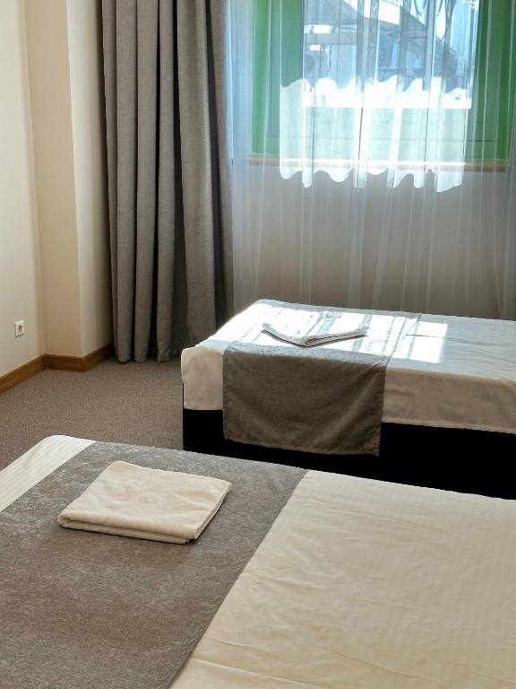 two beds in a room with a window at PORT INN Hotel in Astana