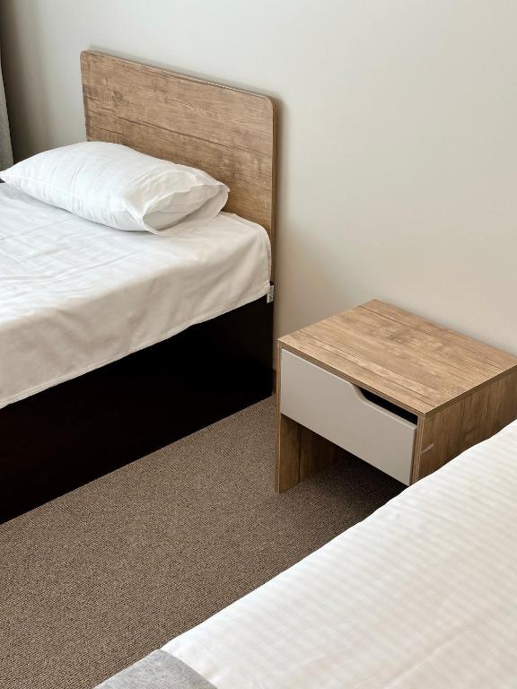 a bedroom with two beds and a wooden table at PORT INN Hotel in Astana