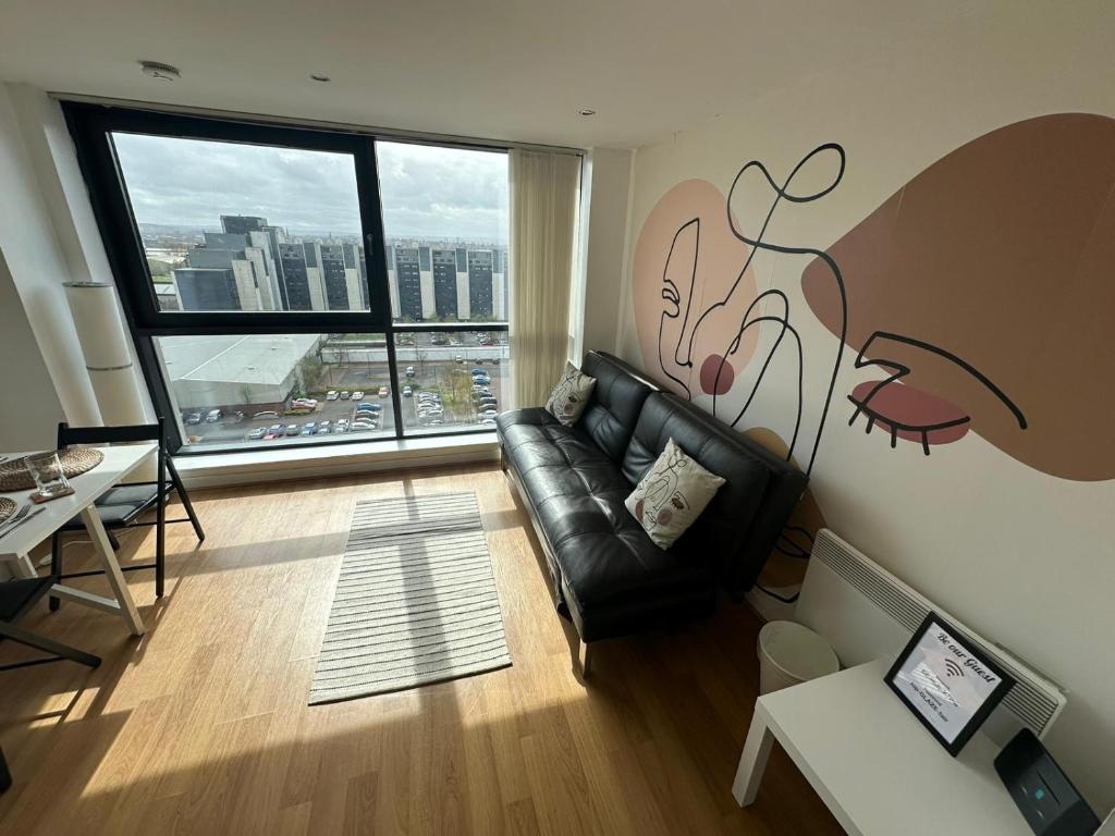uma sala de estar com um sofá de couro e uma grande janela em Pass the Keys Cosy 1 bed next to SEC, OVO Hydro, Finnieston em Glasgow