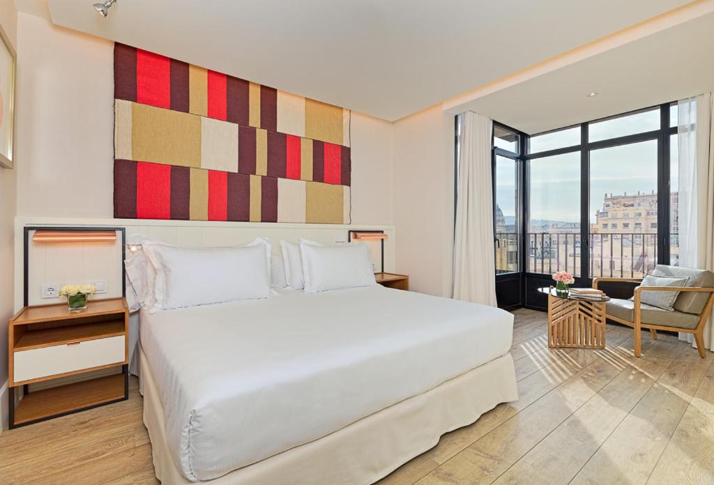 a bedroom with a white bed and a large window at H10 Cubik 4* Sup in Barcelona