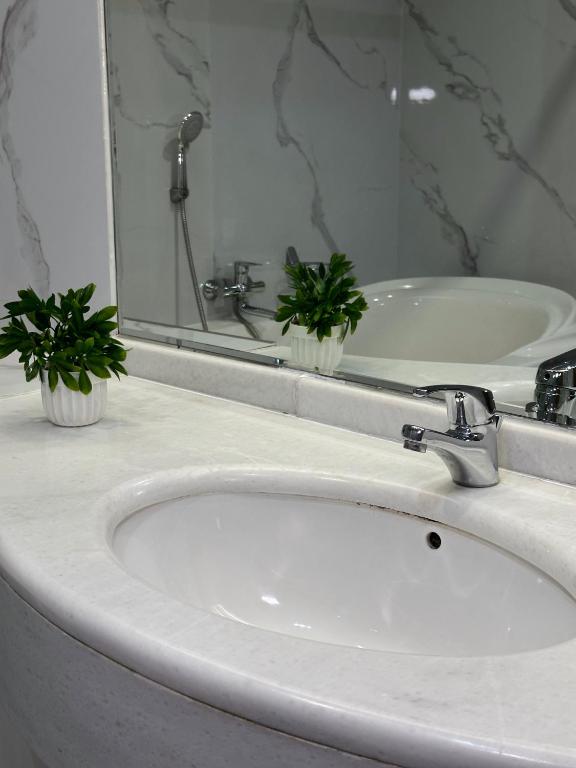 a bathroom sink with a faucet and a mirror at PORT INN Hotel in Astana