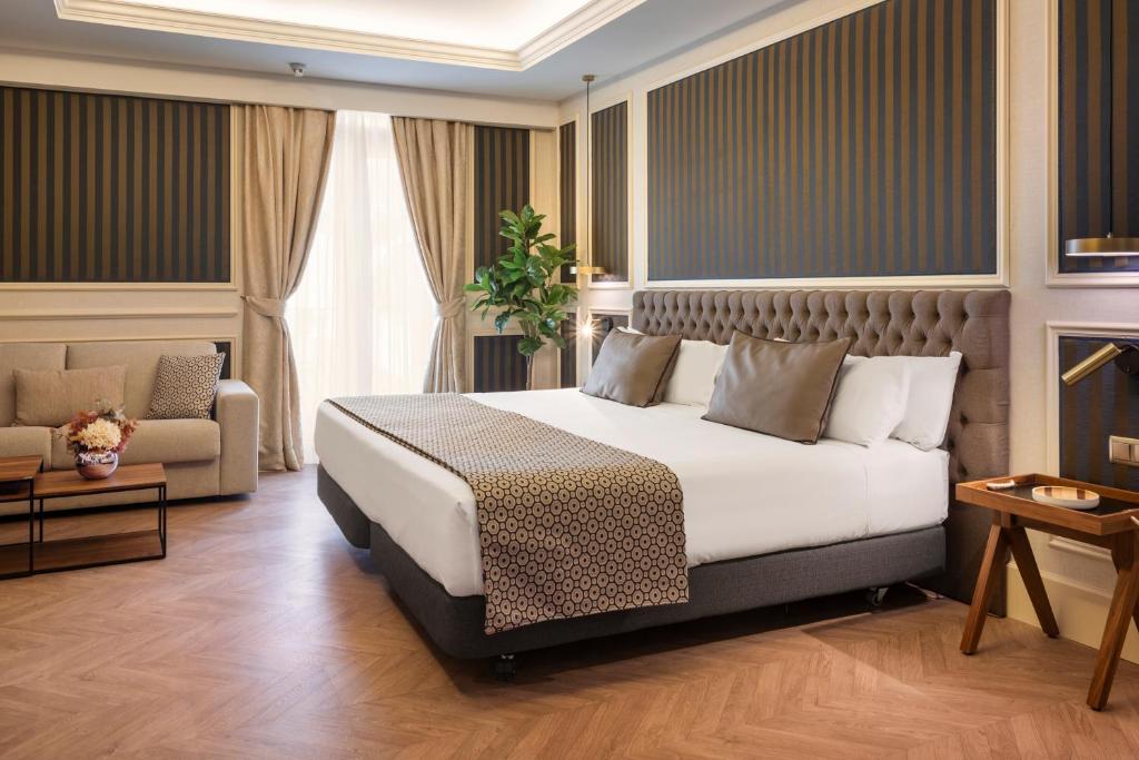 a hotel room with a bed and a couch at Catalonia Las Cortes in Madrid