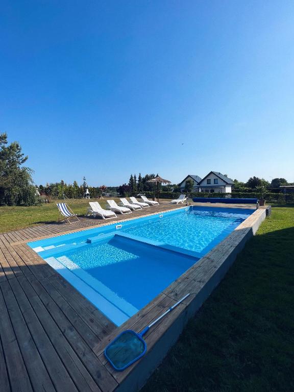 una piscina su una terrazza in legno con sedie intorno di Ostrovia - pokoje nad morzem a Ostrowo
