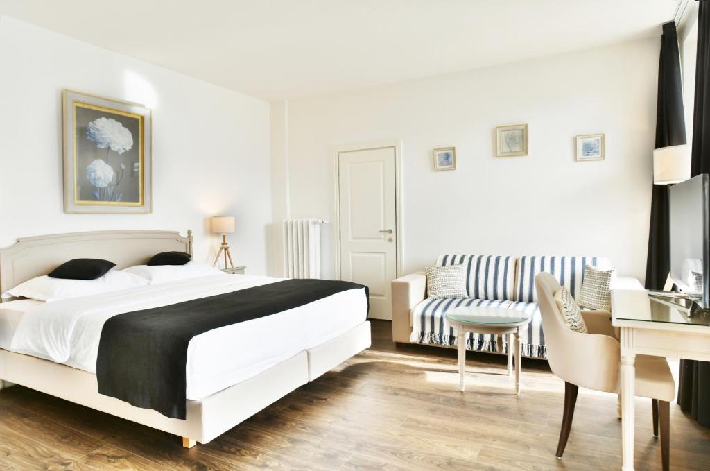 ein weißes Schlafzimmer mit einem Bett und einem Schreibtisch in der Unterkunft Baron Tavernier Hotel Restaurant & SPA in Chexbres