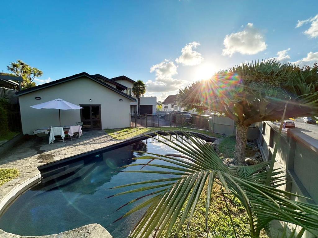 una piscina con una palmera al lado de una casa en 2 Beddie by the Bay, en Auckland