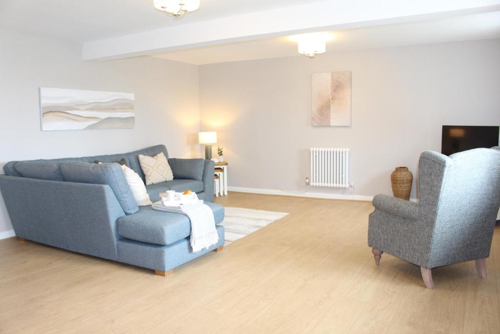 a living room with a blue couch and two chairs at Seashell Cottage in Llanddulas