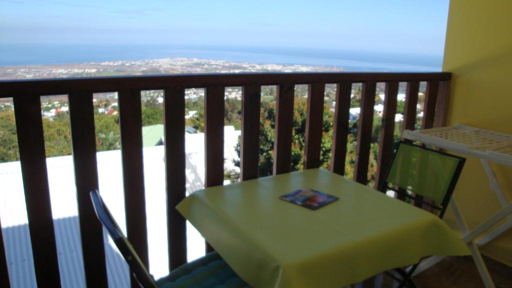 een tafel en stoel op een balkon met uitzicht op de oceaan bij Location Alpinia in Saint-Paul