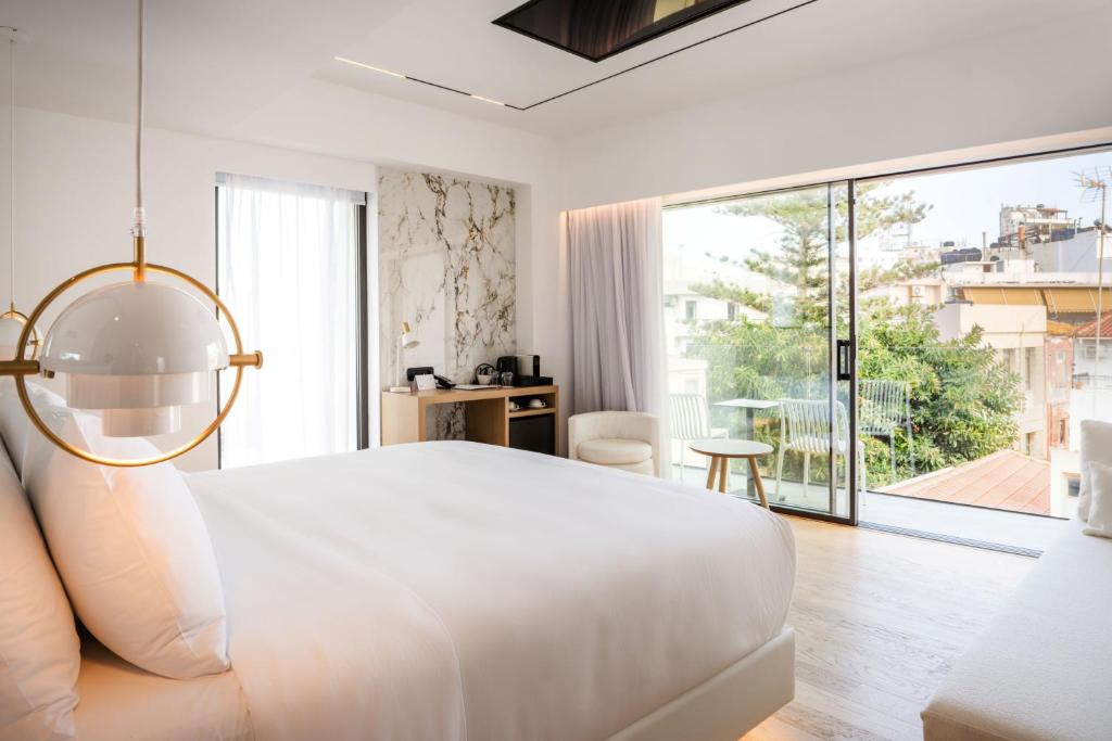 a white bedroom with a large bed and a large window at Ethereal White Resort & Spa in Heraklio