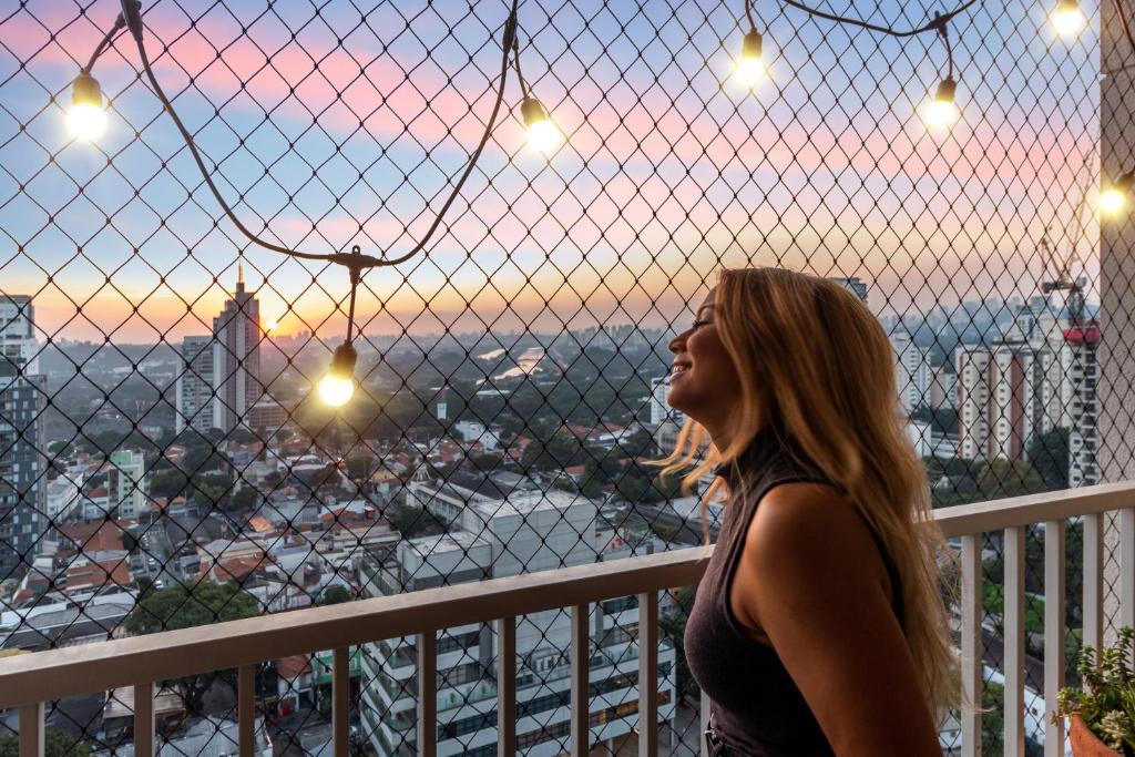 a woman standing on a balcony looking out at the city at Oasis Urbano Faria Lima in São Paulo