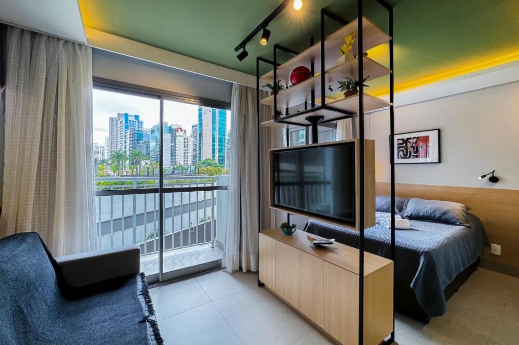 1 dormitorio con 1 cama, TV y ventana en Studio novíssimo, completo e muito bem localizado, en São Paulo